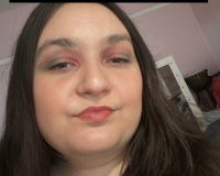 An image of a young woman with shoulder length dark brown hair and brown eyes wearing colourful makeup.
