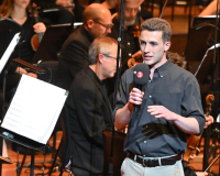 Liam speaking in front of an orchestra