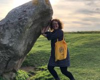 Libby pretending to hold up a large stone at Avebury
