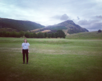 a landscape image of Arthur's Seat with a small figure of a woman in black jrans and a white t shirt in the foreground
