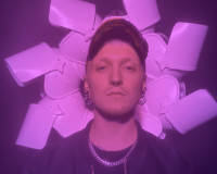 A white person wearing a hat in pink lighting