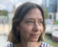 White woman with shoulder length brown/grey hair