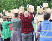 Photo of a group of people with their backs to the camera holding audio speakers in the air