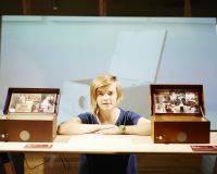Chloe a white queer woman in her 30s is next to two music memory boxes, her project for people living with dementia.