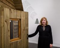 A woman standing next to a wooden shed