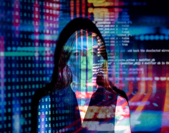 Image of a women with multi-coloured projections of coding over her