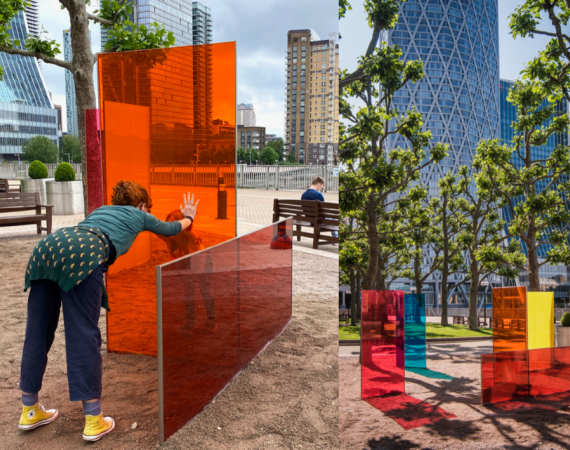 Two people with their hands touching each others through coloured glass