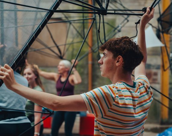 Several people supporting a structure out of view