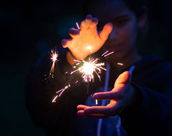 A spark is contained by two hands lit up by the glow