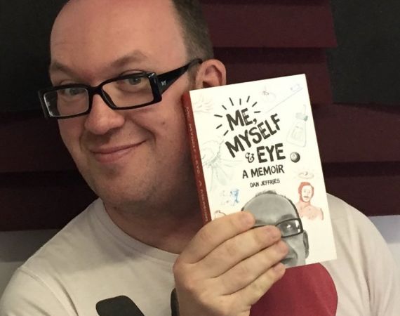 a white man with glasses holding up a paperback book: "Me, Myself & Eye: A Memoir"