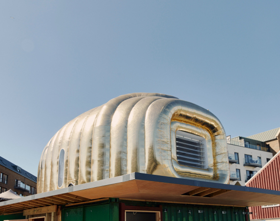 An image of the golden Martian house, set up on a platform the M Shed Square