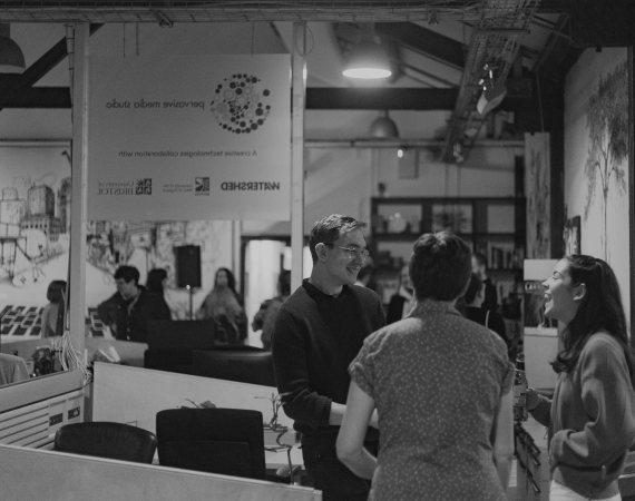 Black and white photo of people gathered in Pervasive Media Studio for an event