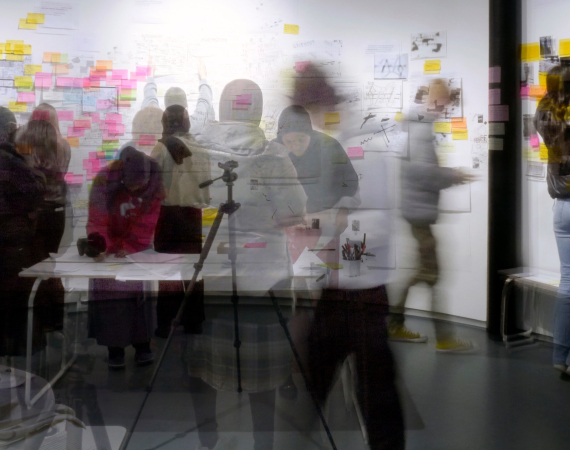 Research students gather in front of their project wall at the PHD research event.
