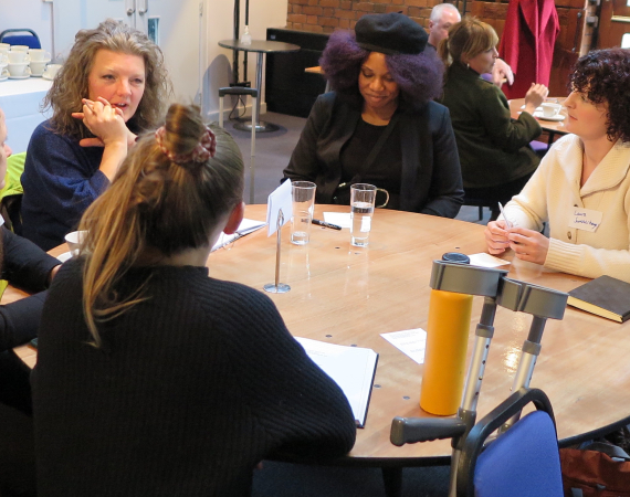 An image of a diverse group of creatives sat around a table at a meeting. 