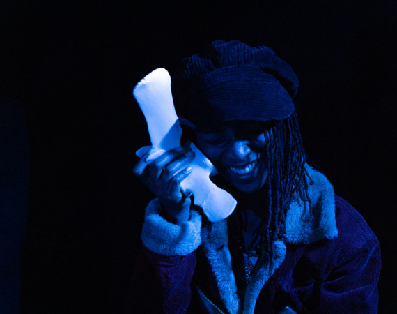 An image of a woman holding a sanitary pad like a phone, and smiling in a blue light.