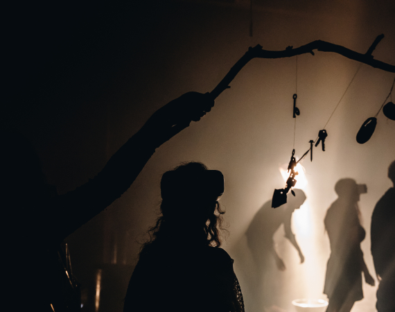 Multiple people experience the work Starless in VR headsets - they are cast in silhouette against a strong, white light.