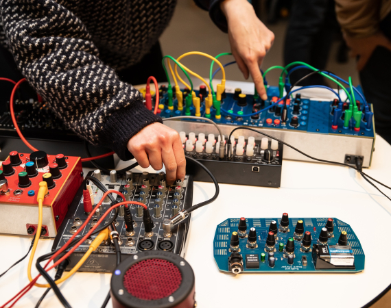 Hands turn dials on a home made synth