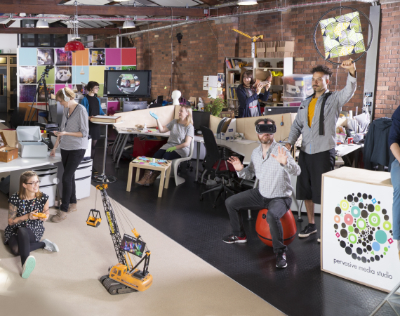 Pervasive Media Studio with studio residents and staff holding up projects
