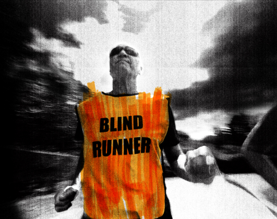 A fisheye camera angle points back at Phil, a blind runner. He wears a bright orange hi-vis tabbard with ‘blind runner’ in large capitals, dark wrap-around sunglasses and clutches a luminous yellow tether that connects him to his guide runner. The whole image is treated with a high-contrast, punk-inspired photocopy texture in black and white, with the accent colours roughly scribbled on top with a highlighter marker.