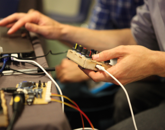 Two hands holding several bits of electronic equipment