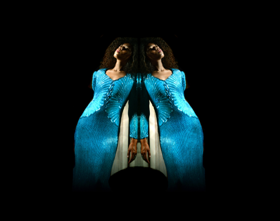 An image of the voice artist Angelica Allen. She is posing in the centre of the image, and is mirrored, creating a rorschach-test like image of two Angelicas side by side, seemingly leaning on each other. 