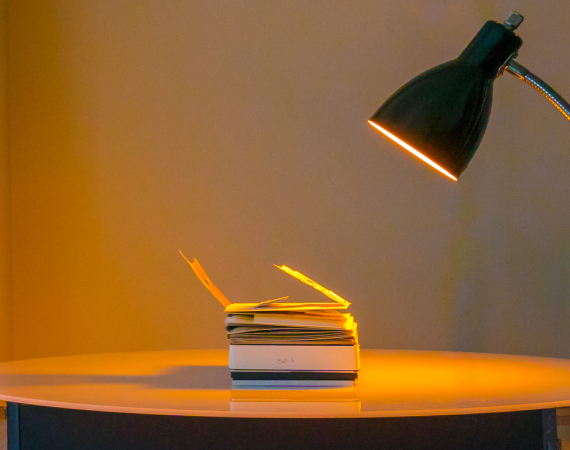 An image of Sister Sylvester's hand made book Constantinopoliad lying flat on a table, illuminated in a warm orange by a nearby desk lamp. 