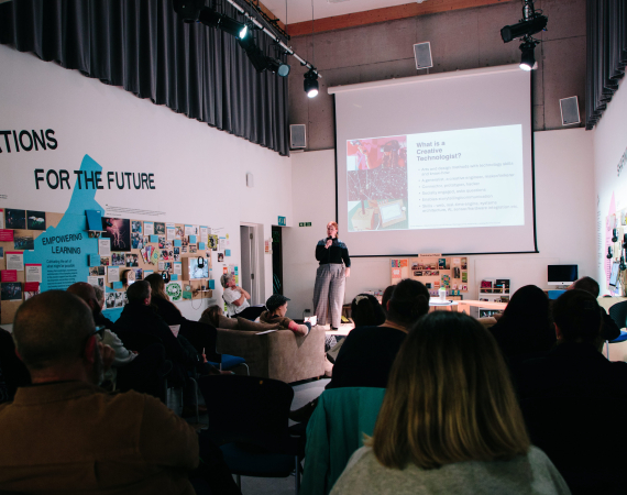 An image of Coral Manton giving a talk on the role of the Creative Technologist to a large audience. 