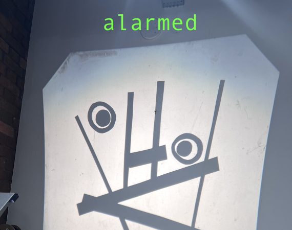 Projected abstract face with geometric shapes and circles conveys alarmed emotion. The word "alarmed" is displayed above in green text.