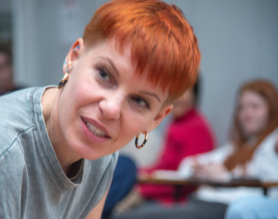 A white woman with short dyed red hair looks away from the camera