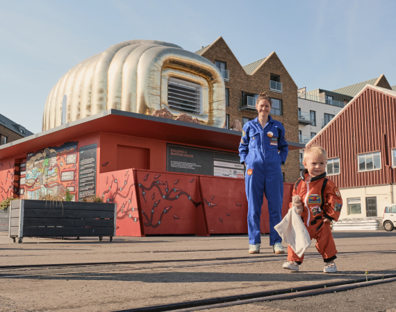 A woman and child stand in front of a golden structure 