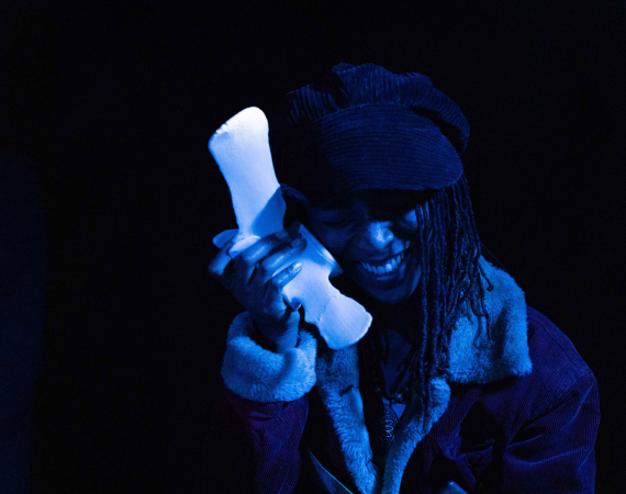 A woman smiles, holding a phone like object to her ear