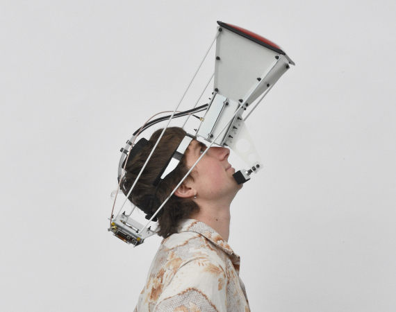 A person wearing a large projector-like device strapped to their face, gazes up.