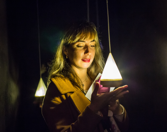 Image of woman holding triangular shaped lamp