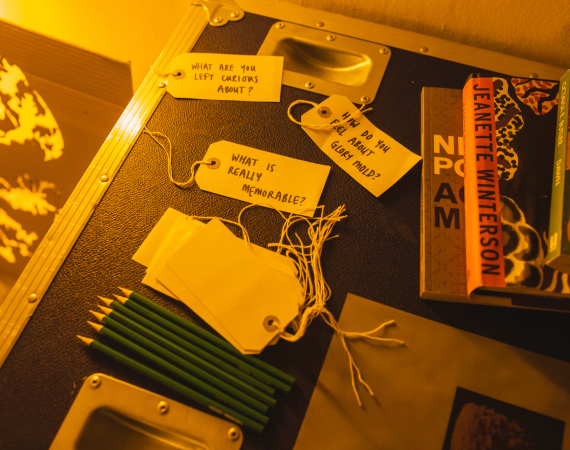 a desk with pencils, books and some luggage labels with questions
