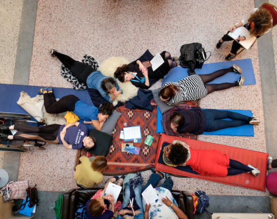 Photo from above of community members laying down in thought holding notepads