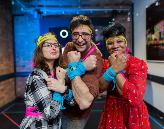 Three people stand in the Studio, posing in costume as part of a game