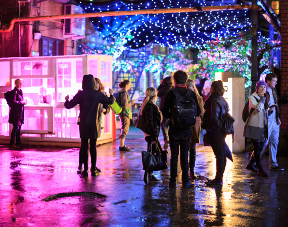 Image of people convening in a lit up outdoor area