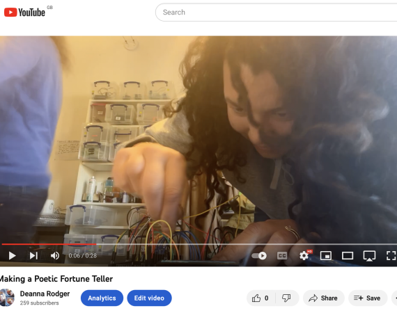  screen shot of a YouTube video I though I had uploaded. A woman with thick curly hair is leaning over a table putting wires into a breadboard.