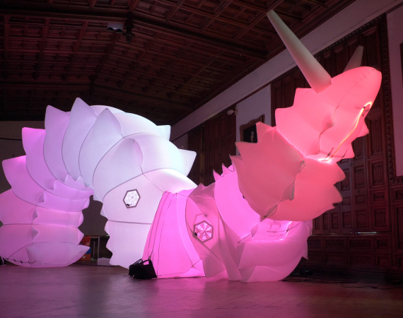 A large pink inflatable robotic snail inside a large hall.