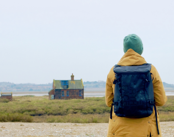 The author stands looking at a derelict house in the distance