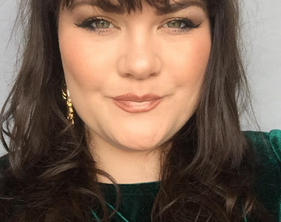 this image show scarlett smyth, wearing a green velvet dress, a woman, smiling into the camera.