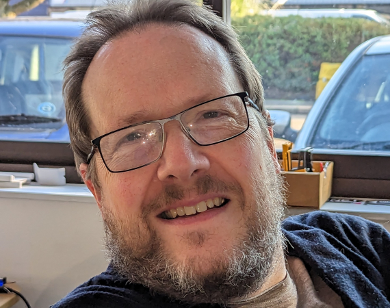 A bearded white man in his fifties wearing glasses