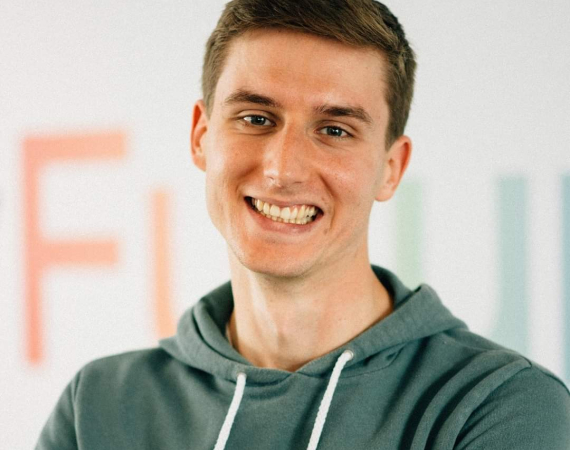 White man with light brown hair wearing a green hoody