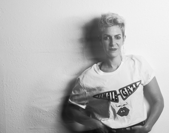A black and white shot of Joss. They are standing against a light background.