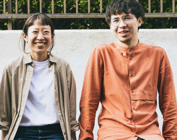 An image of Saki (left) and Dan (right) from playfool - they sit looking at the camera, smiling.