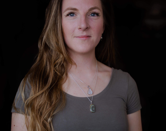 Portrait of Hannah Southfield, a person with long hair and a grey top against a dark background