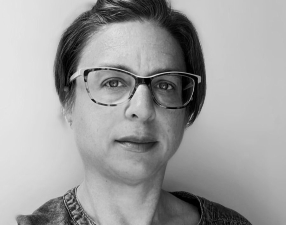 A black and white photograph of a white woman in her 40s with short hair and glasses
