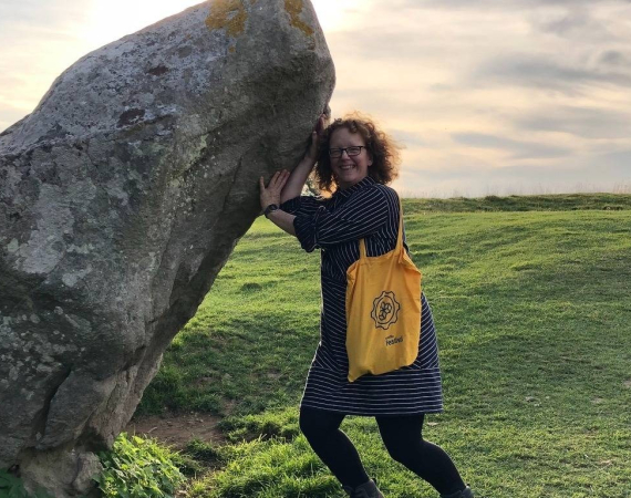 Libby pretending to hold up a large stone at Avebury