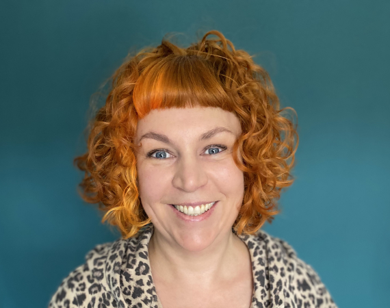 White woman in her 40's with curly orange hair
