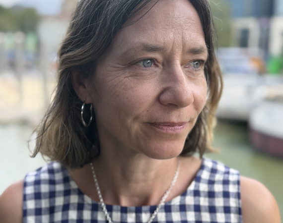 White woman with shoulder length brown/grey hair
